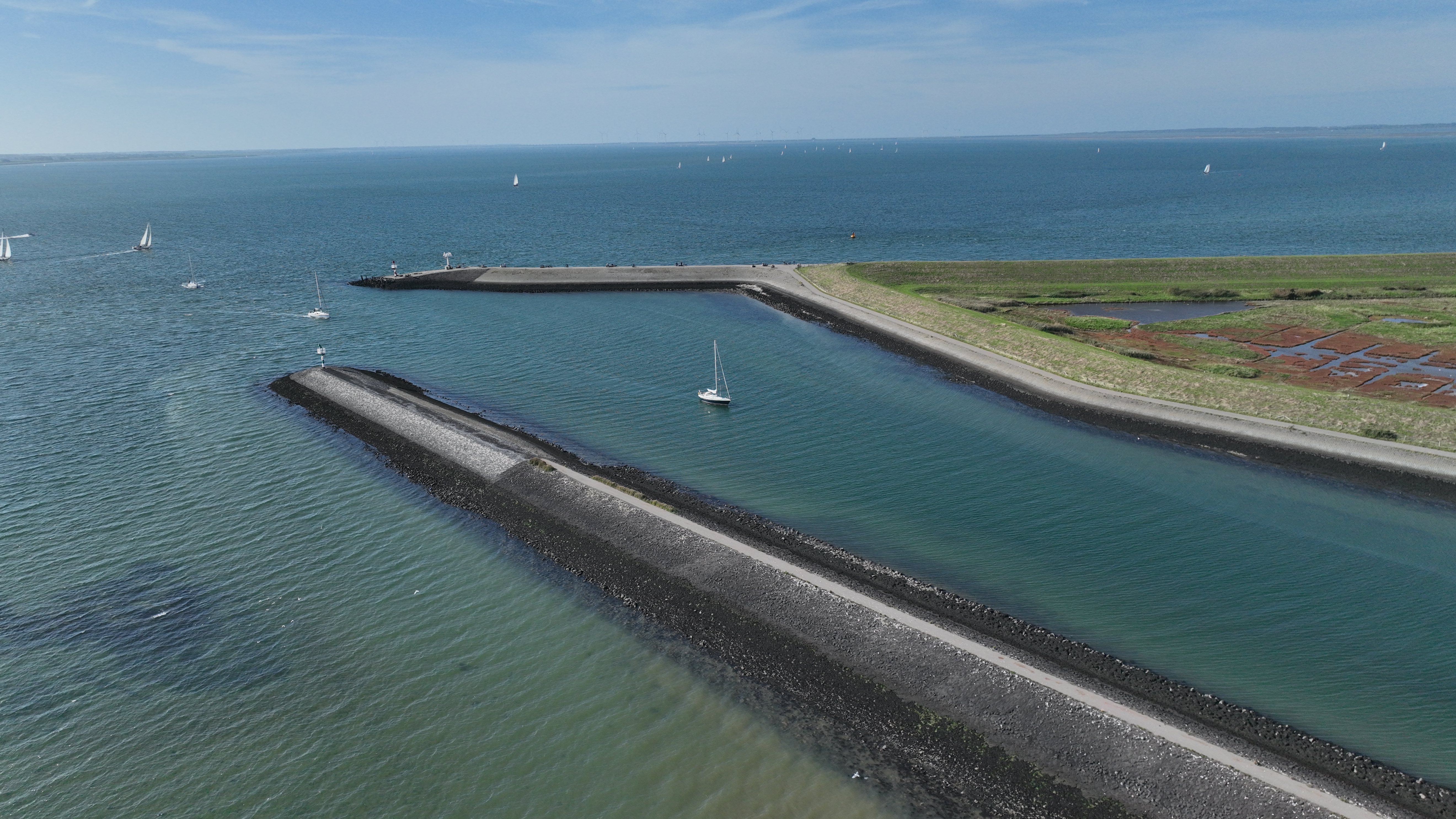 Luchtfoto van strekdammen en zeilboten op het water in Zeeland