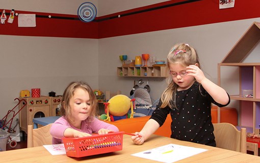 Twee kinderen aan het kleuren aan tafel bij de kinderopvang.