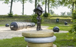 Speeltuin met gouden en zilveren munten met een pagadder op de uitkijk. Op de achtergrond een kanon om op te spelen.