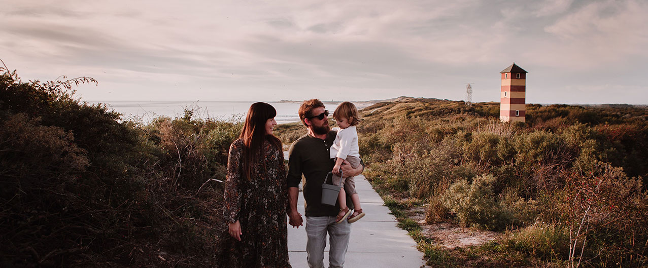 Zonsondergang in de duinen met familie op de voorgrond en op de achtergrond de zee en strand dishoek